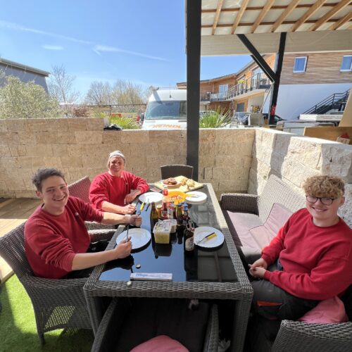 Das Holzbau Reindl Team genießt Brotzeit auf der Terrasse eines Hauses