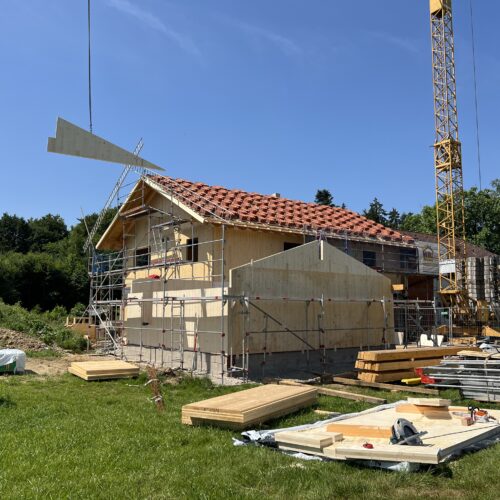 Kran hebt Bauelemente auf eine Holzhaus-Baustelle